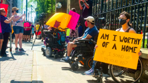 Disability Justice advocates protesting with a signs. 